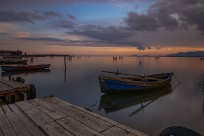 Boats moored in lake against sky during sunset