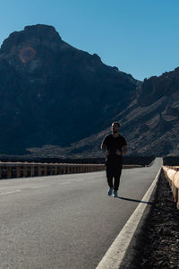 Full length of man standing on road against mountain range