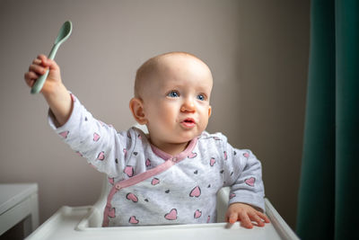 Portrait of cute baby boy sitting on table at home