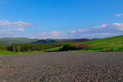 Surface level of road amidst field against sky