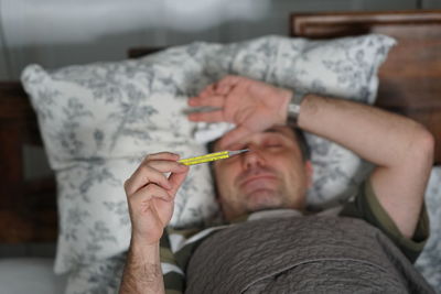 Man checking temperature while lying on bed at home