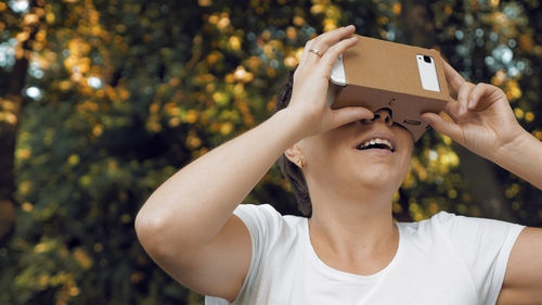 Woman using google cardboard against trees