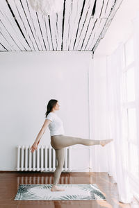 Side view of woman standing against white wall