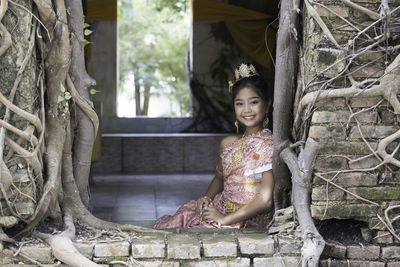 Portrait of smiling woman sitting on tree trunk