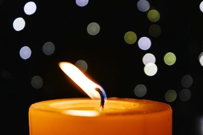 Close-up of lit candle at night