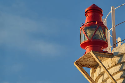 Low angle view of lighthouse by building against sky