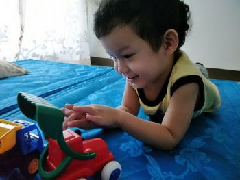 Close-up of smiling boy sitting in bedroom