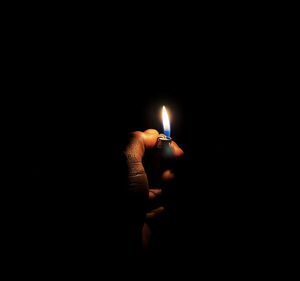 Close-up of hand holding lit candle in the dark