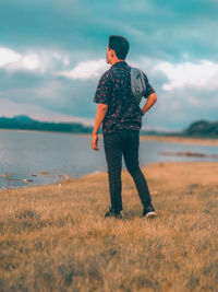 Rear view of man standing on field against sky