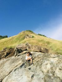 Man standing on rock against clear blue sky