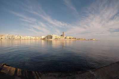 View of buildings by sea against cloudy sky