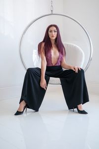 Portrait of a young woman sitting against wall