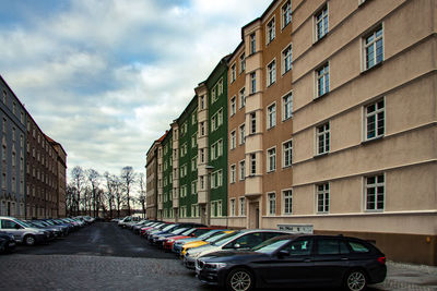 Cars on road by buildings in city against sky