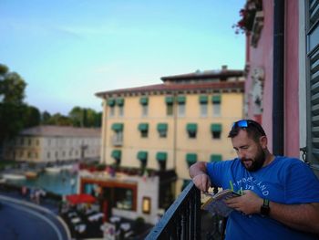 Man looking at building against blue sky