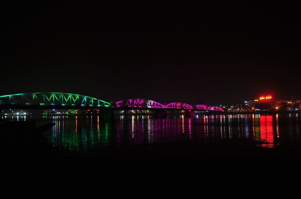 ILLUMINATED BRIDGE OVER RIVER AT NIGHT