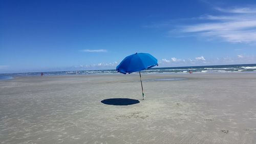 Umbrella at sandy beach against sky