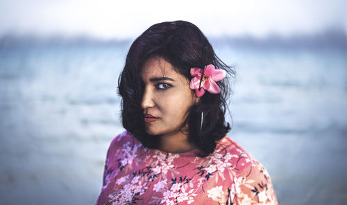 Portrait of young woman standing against sea