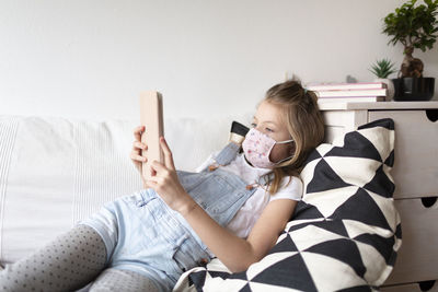 Girl using mobile phone on sofa at home