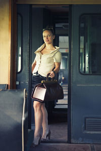 Portrait of young woman standing by train