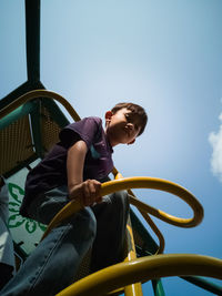 Low angle view of boy standing on play equipment