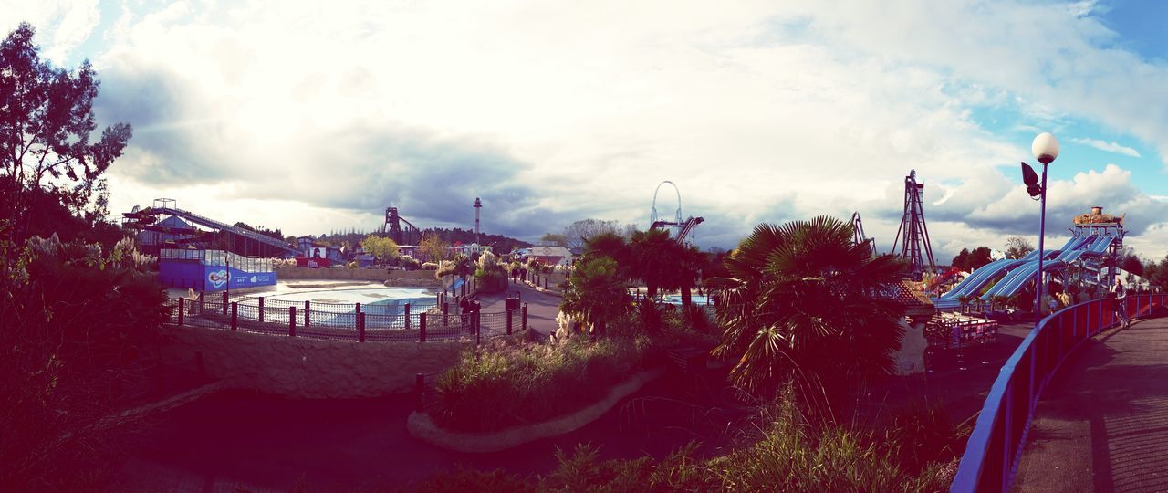 sky, cloud - sky, built structure, architecture, cloudy, tree, building exterior, cloud, transportation, nautical vessel, mode of transport, amusement park ride, outdoors, amusement park, panoramic, day, travel, city, nature, arts culture and entertainment