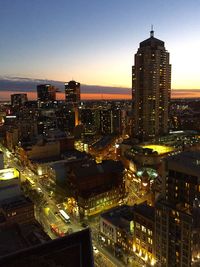 Illuminated cityscape against sky during sunset