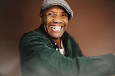 Cheerful mature man by brown background in studio