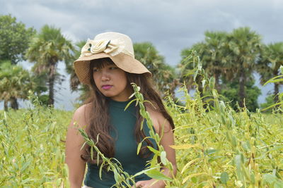 Young woman wearing hat standing amidst plants on field