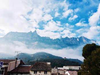 Houses on mountain against cloudy sky