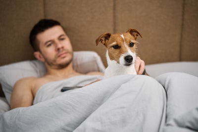 Portrait of dog sitting on bed at home