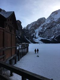 People on snowcapped mountain against sky during winter