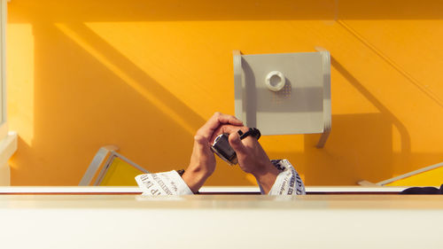 Cropped image of man holding camera over yellow flooring