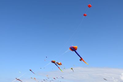 Low angle view of balloons flying against clear blue sky