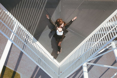 High angle view of young woman lying down on elevated walkway