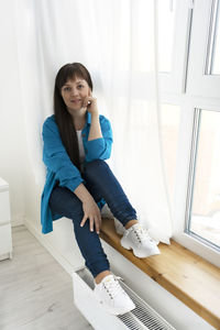 Portrait of young woman sitting on floor at home