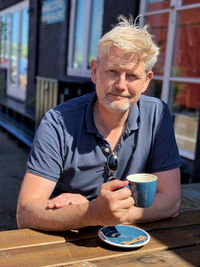 Portrait of man drinking coffee while sitting at table 