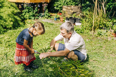 Grandfather and granddaughter gardening in yard
