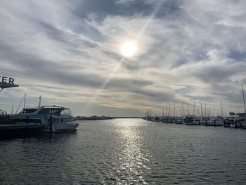 Sailboats in marina at harbor against cloudy sky