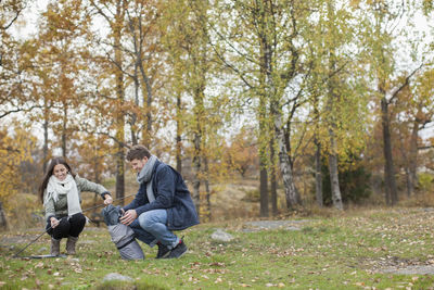 Full length of couple pitching tent in forest