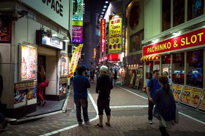 Full length of man standing on illuminated city street at night