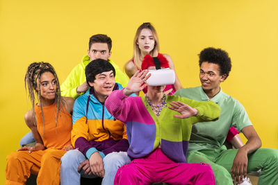 Young couple sitting on smart phone against yellow background