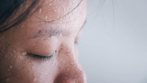 Close-up of woman with eyes closed against white background