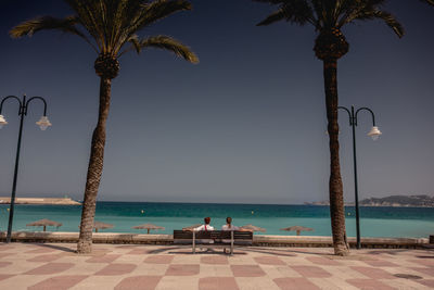 Rear view of couple overlooking calm blue sea