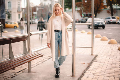 Portrait of smiling young woman standing on bus stop in city