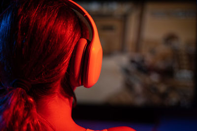 Rear view of a caucasian woman playing a computer game in neon light in the dark