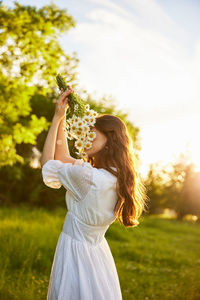 Side view of woman with arms raised standing on field