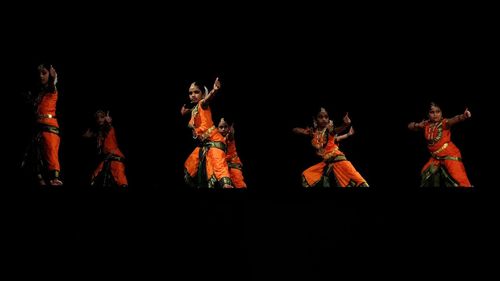 Group of people dancing against black background