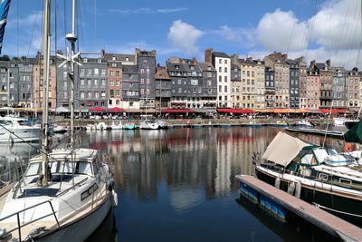 Boats moored at harbor against buildings in city