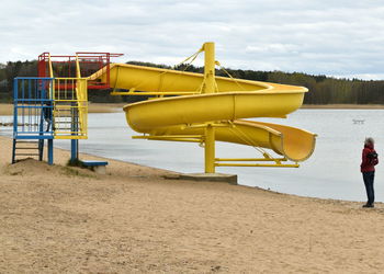 Deck chairs on beach against sky