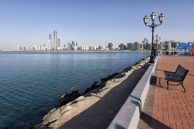 Sea by modern buildings in city against sky